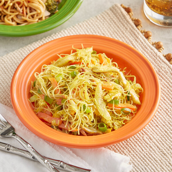 An Acopa Valencia orange stoneware plate with noodles, vegetables, and meat.