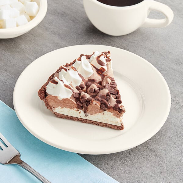 A piece of Acopa ivory stoneware plate with a slice of chocolate pie topped with whipped cream and chocolate chips.