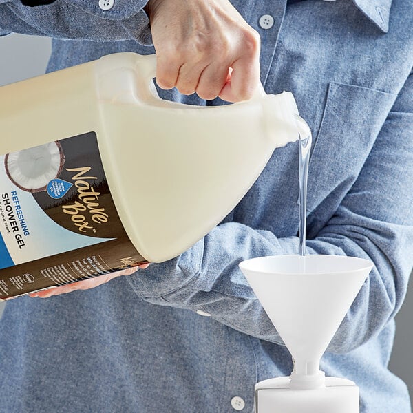 A person pouring Dial Nature Box Coconut Oil Body Wash into a plastic container.