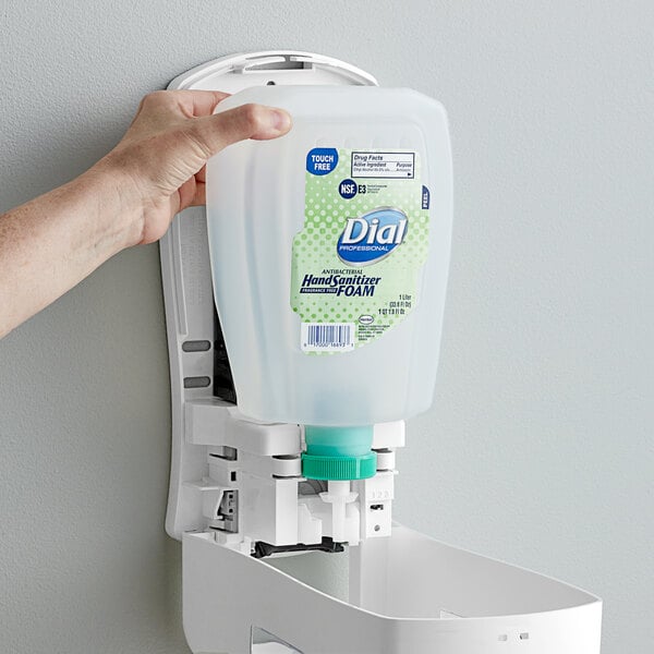 A hand holding a white Dial hand sanitizer refill in a soap dispenser.