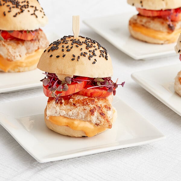 A close up of three small sandwiches with tomatoes, cheese and bread.