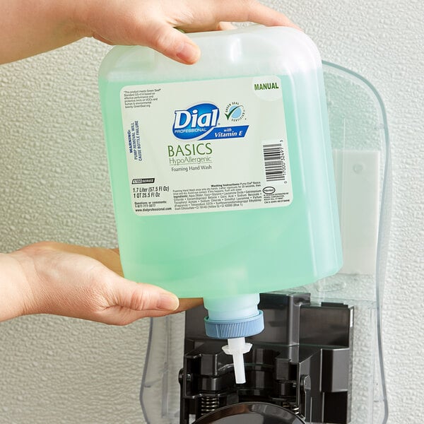 A person holding a Dial Basics Hypoallergenic Vitamin E foaming hand wash refill bottle over a soap dispenser.