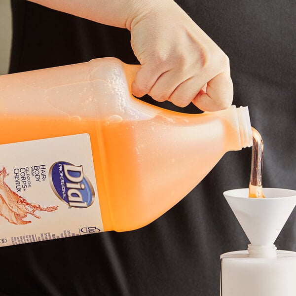 A hand pouring Dial Hair and Body Wash from a white funnel into a plastic bottle.