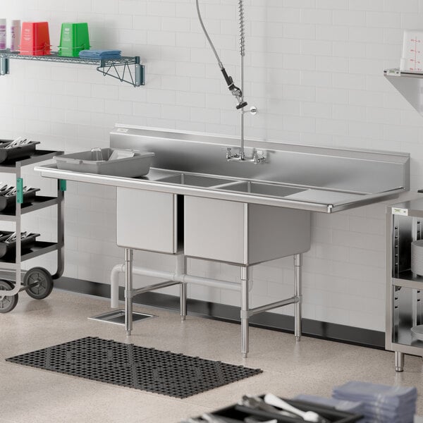 A Regency stainless steel two compartment sink with drainboards on a kitchen counter.