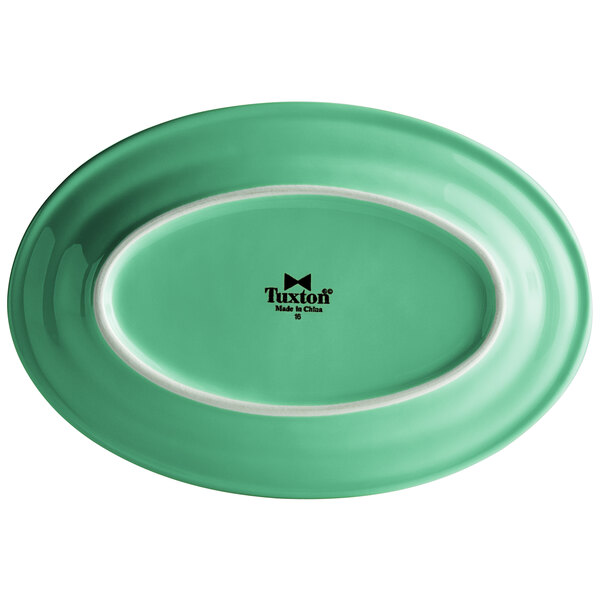 A green Tuxton oval china platter with a white edge.
