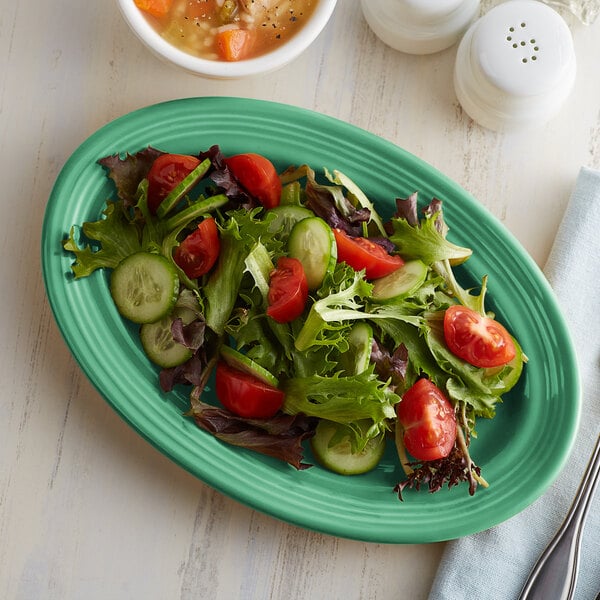 A Tuxton Cilantro oval china platter with salad and soup on it.