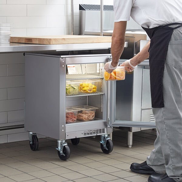 A man putting oranges into a Beverage-Air undercounter refrigerator.