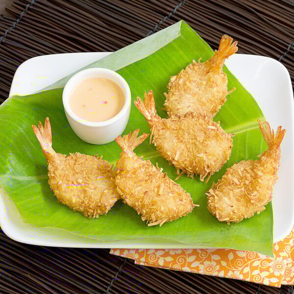 Breaded butterfly shrimp on a plate with sauce.