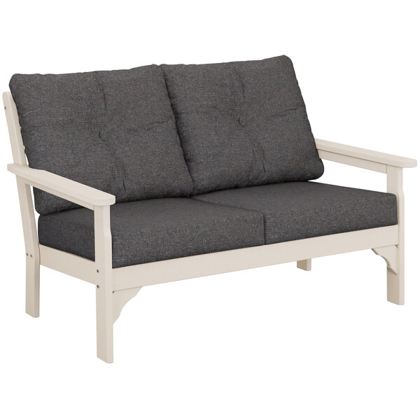 A grey POLYWOOD Vineyard settee with white cushions.