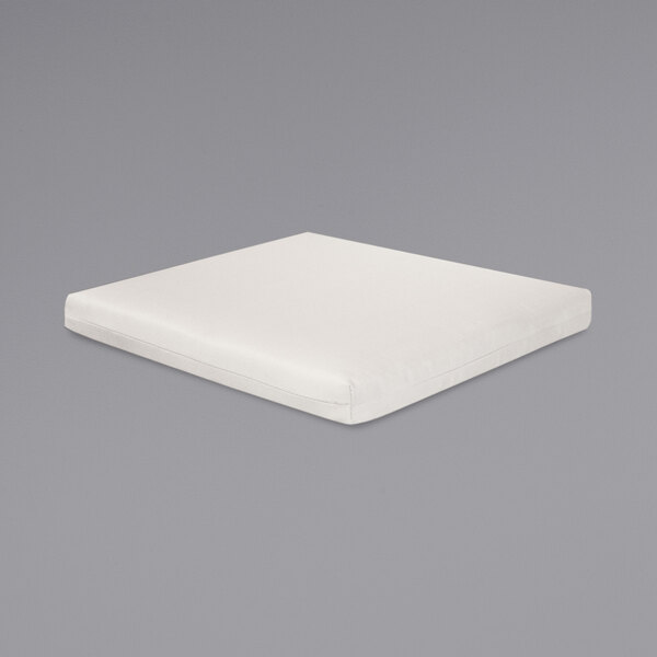 A white square pillow on a gray surface.