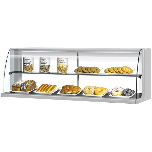 A Turbo Air stainless steel high profile dry display case on a counter in a bakery with a variety of pastries on shelves.