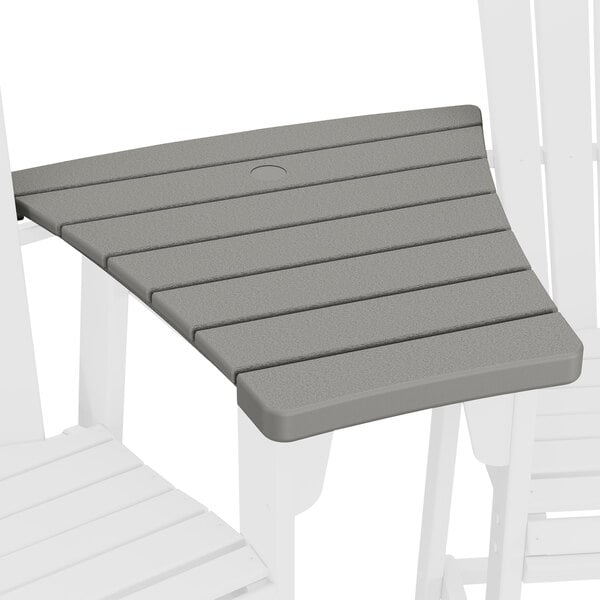 A slate grey POLYWOOD Adirondack chair connected to a slate grey POLYWOOD dining table outdoors.