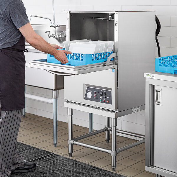 A man standing in a kitchen with a Noble Warewashing undercounter dishwasher.