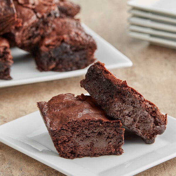 A plate of brownies with a fork and knife on a white table.