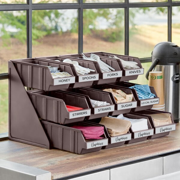 A brown 3-tier self-serve organizer with bins holding utensils.