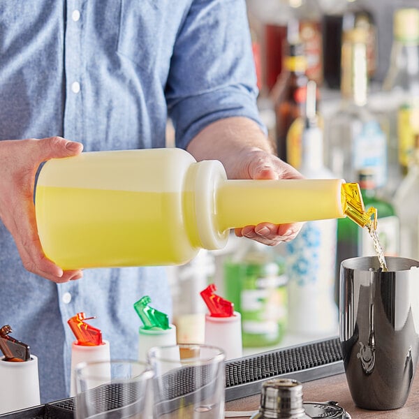 A person pouring yellow liquid from a Choice pour bottle into a glass.