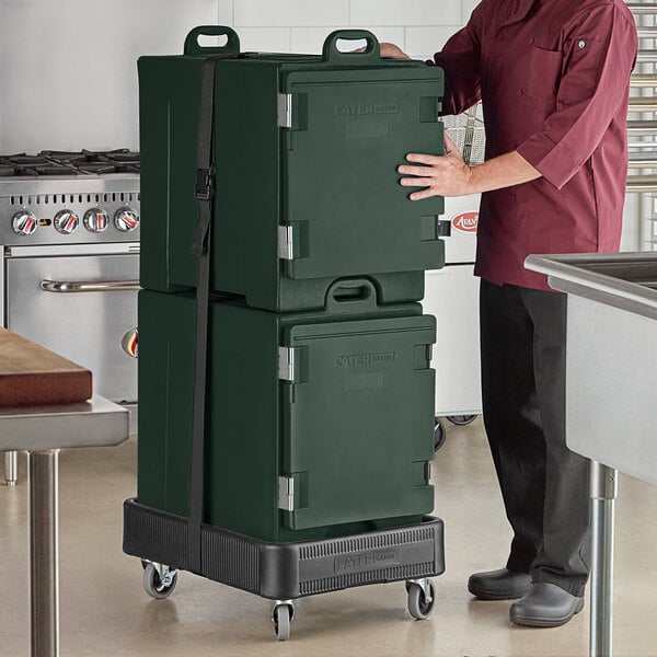 A man in a chef's uniform holding a green CaterGator pan carrier box.