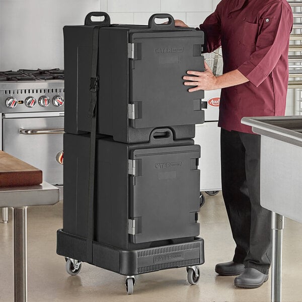 A man in a chef's uniform holding a stack of black CaterGator pan carriers.