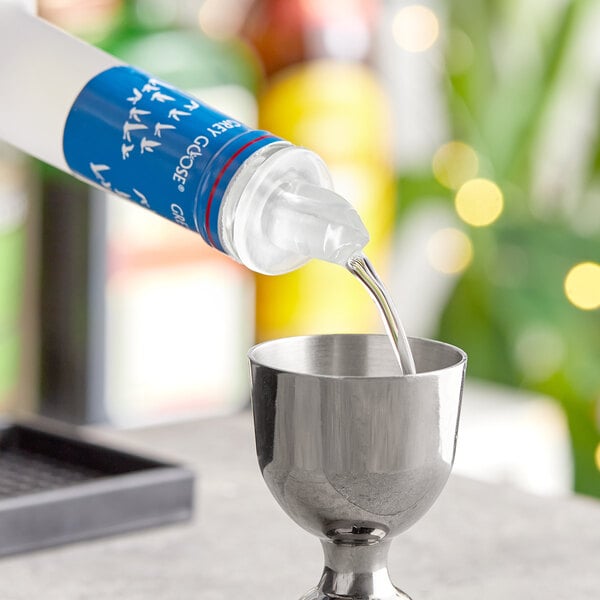 A person using a Choice clear free flow liquor pourer to pour liquid into a cup.