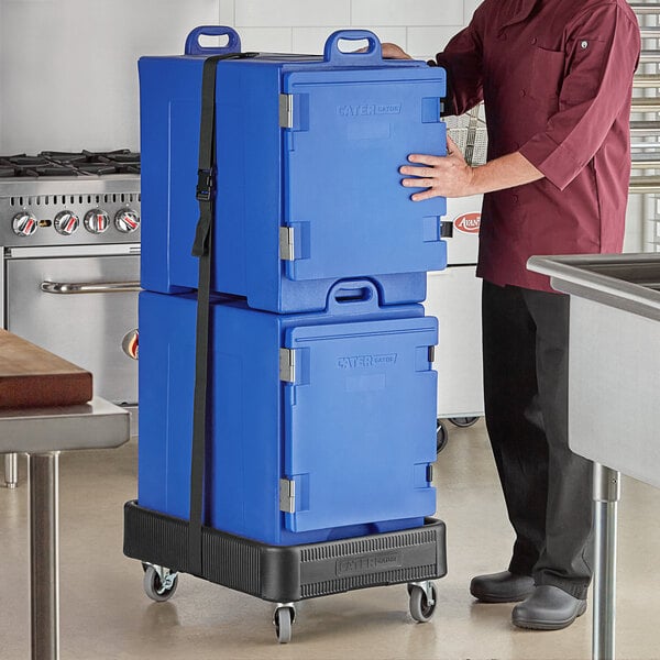 A man using a strap to carry two blue CaterGator pan carriers.