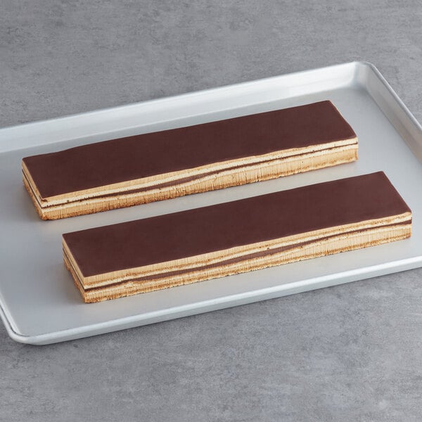 Rectangular white toque opera strip cakes covered in chocolate on a white tray.