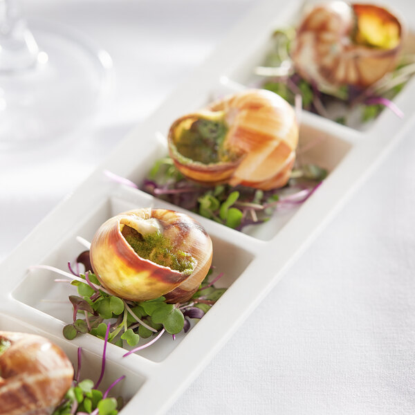 A white plate with four White Toque escargot in shells on it.