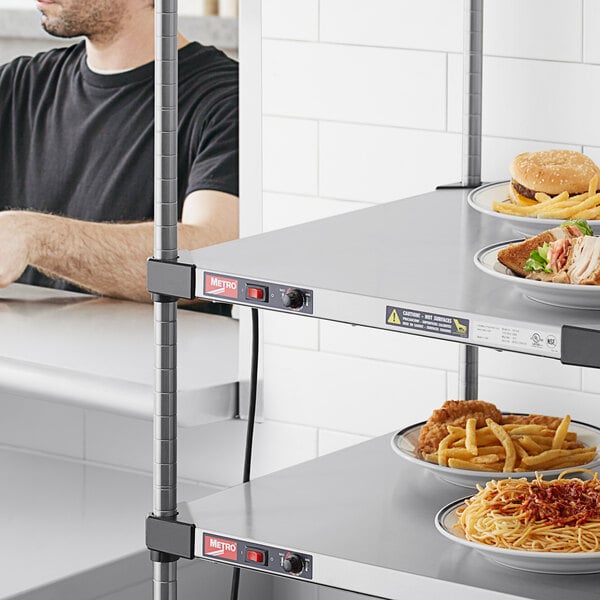 A man sitting at a hospital cafeteria counter with a plate of food on a heated shelf.