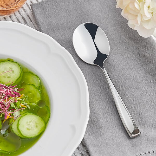 An Acopa Monte Bianco stainless steel bouillon spoon in a bowl of soup.