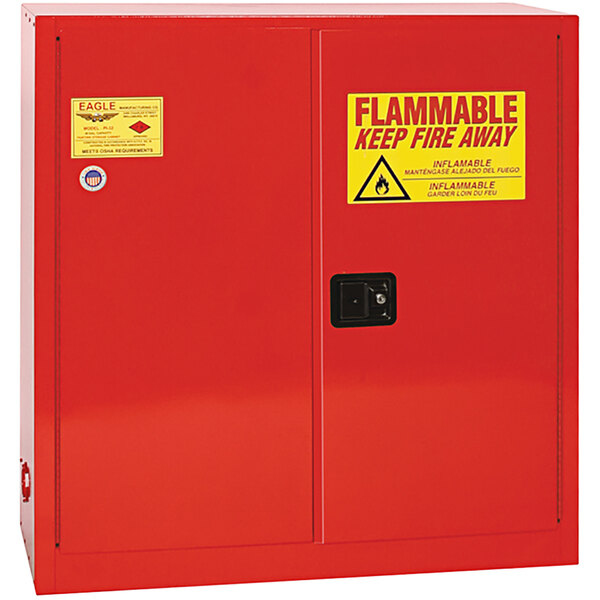 A red metal Eagle Manufacturing safety cabinet with a yellow and red warning sign.