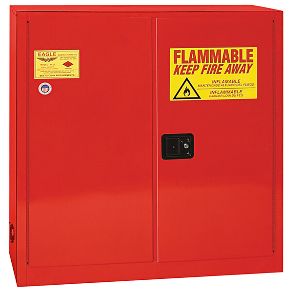 A red metal Eagle Manufacturing safety cabinet with a yellow and red sign with red text.