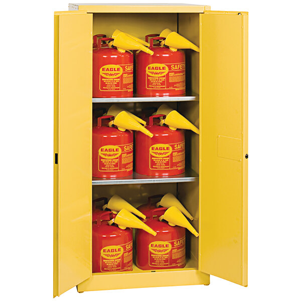 A yellow Eagle Manufacturing safety cabinet with red safety cans inside.