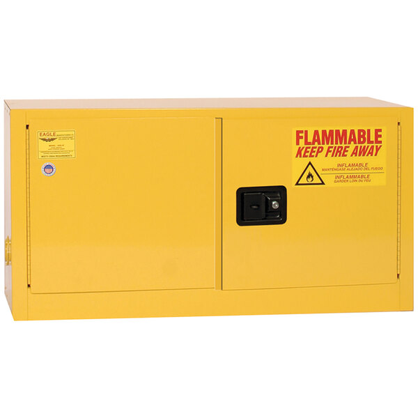 A yellow metal Eagle Manufacturing safety cabinet with 2 black self-closing doors and a red "Flammable" sign.