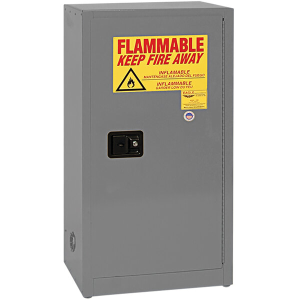 A grey metal Eagle Manufacturing safety cabinet with a yellow sign warning of flammable liquids.