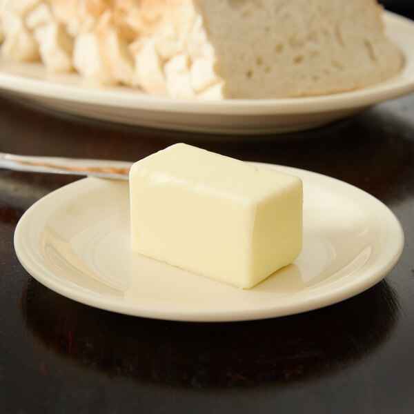 A block of butter on a tan Carlisle bread and butter plate.