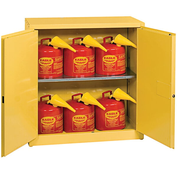 A yellow Eagle Manufacturing safety cabinet with red safety cans inside.