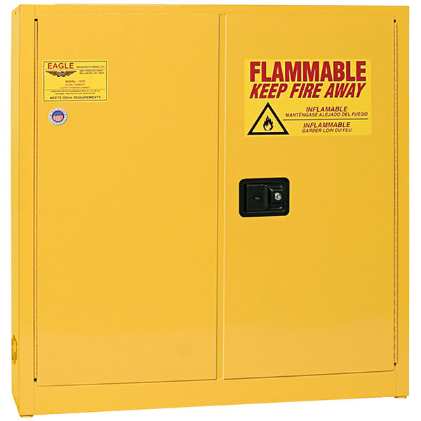 A yellow Eagle Manufacturing safety cabinet with a warning sign on the doors.