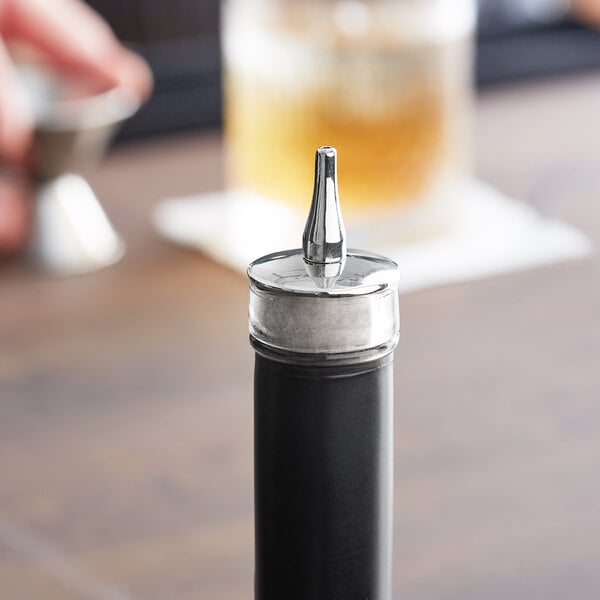 A close-up of a Barfly stainless steel dasher top on a black bottle.
