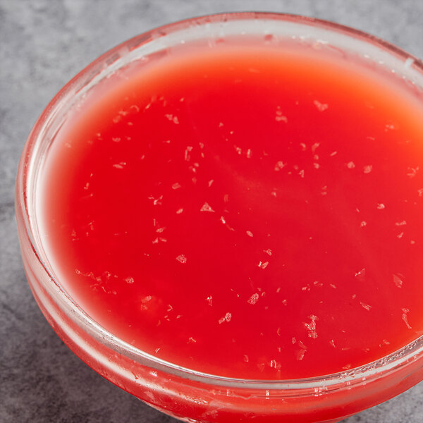 A glass bowl of Les Vergers Boiron Sicilian Blood Orange fruit puree on a counter.