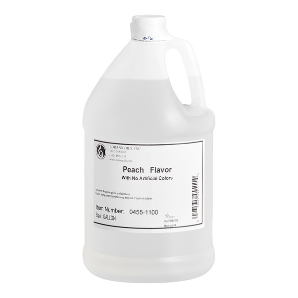 A large, clear plastic jug with a handle and a white label indicating it contains peach flavor with no artificial colors.