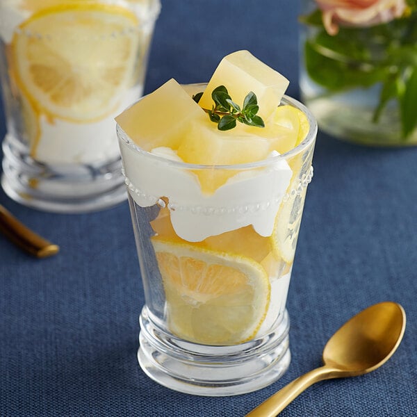 A glass of lemon fruit dessert with a spoon in it.