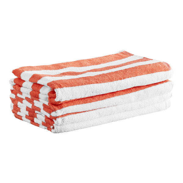 A stack of four folded towels with coral red and white stripes.