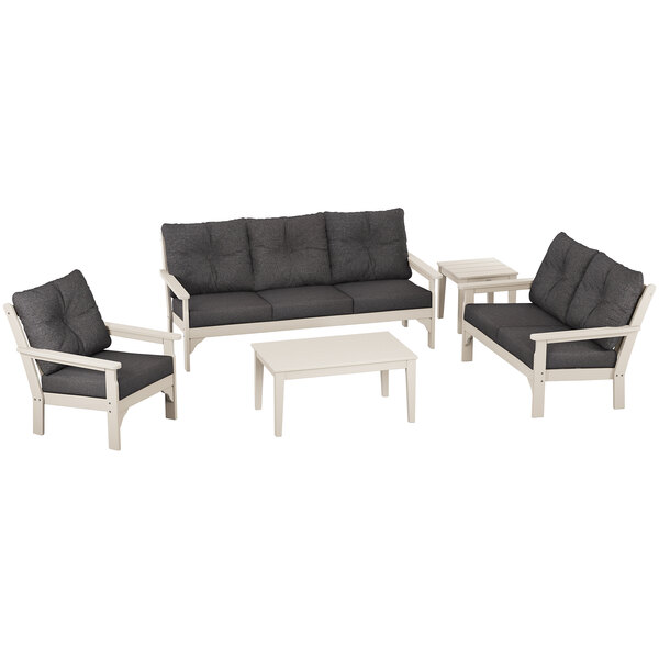 A white and grey POLYWOOD Vineyard deep seating set with black cushions on a white table.