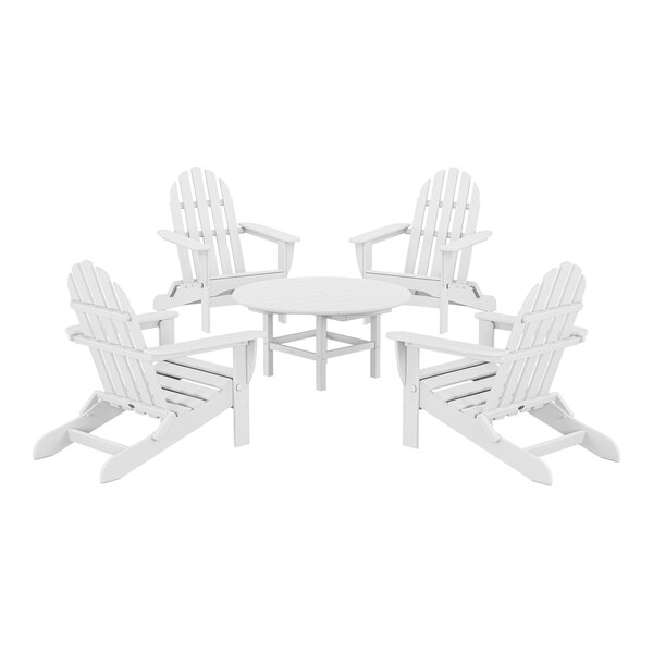 A group of POLYWOOD white Adirondack chairs around a round table.