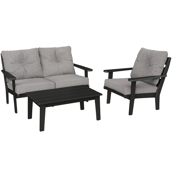 A black and grey POLYWOOD outdoor seating set with a grey couch and chair and a black table.