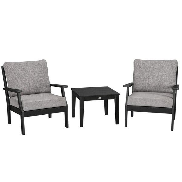 A group of two black and grey POLYWOOD deep seating chairs and a black table with legs.