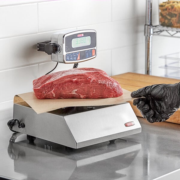 A person weighing a piece of meat on a Tor Rey digital portion scale.