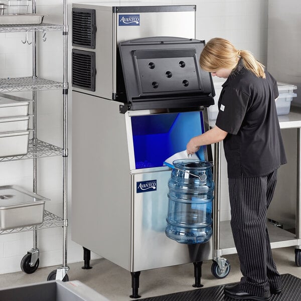 A woman standing in front of an Avantco air cooled full cube ice machine.