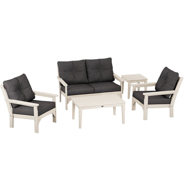 A grey POLYWOOD deep seating chair and table with white armrests, with black cushions on the table and chair.