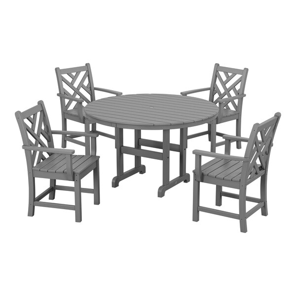 A POLYWOOD slate grey outdoor dining table with four arm chairs around it.