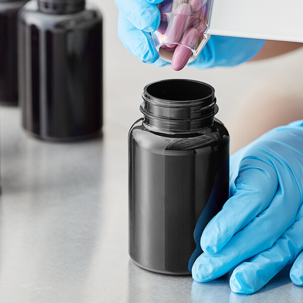 a hand holding a plastic container with pink pills